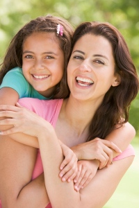 Woman and young girl embracing outdoors smiling